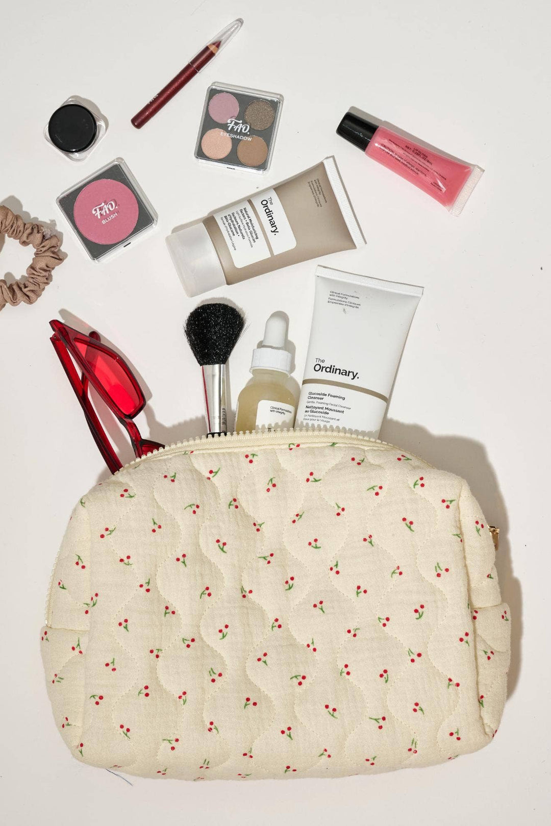 Makeup bag with various cosmetic items on a white background