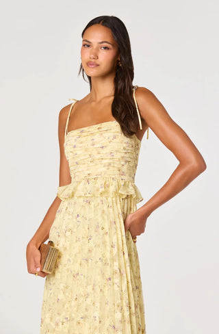 Woman wearing a yellow floral dress against a white background