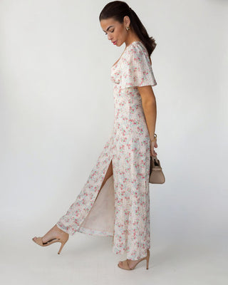 Woman wearing a floral dress with a slit on a white background