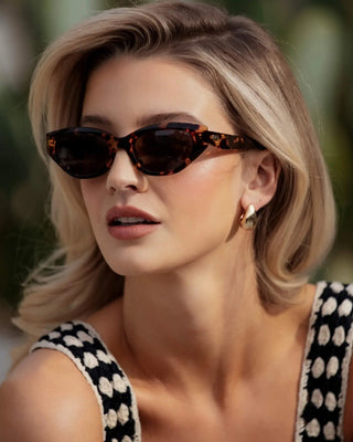 Woman wearing tortoiseshell sunglasses with a blurred natural background