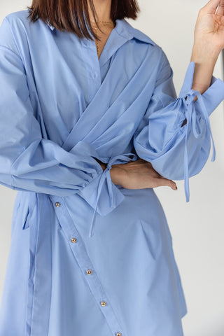 Close up detail of women's Portofino wrap mini dress showing notched collar, button closure and self-tie wrap detail in sky blue