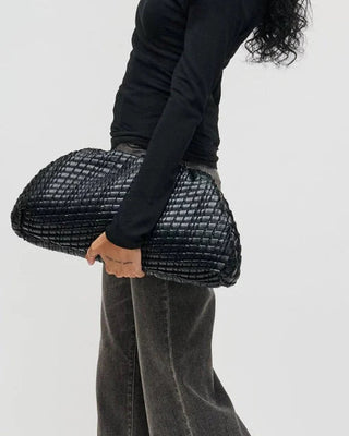 Woman holding a black textured clutch against a white background