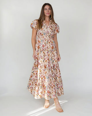 JO+CO Britton floral maxi dress in ecru with a notched V-neck, elasticized waist, and tiered skirt. Made of cotton.